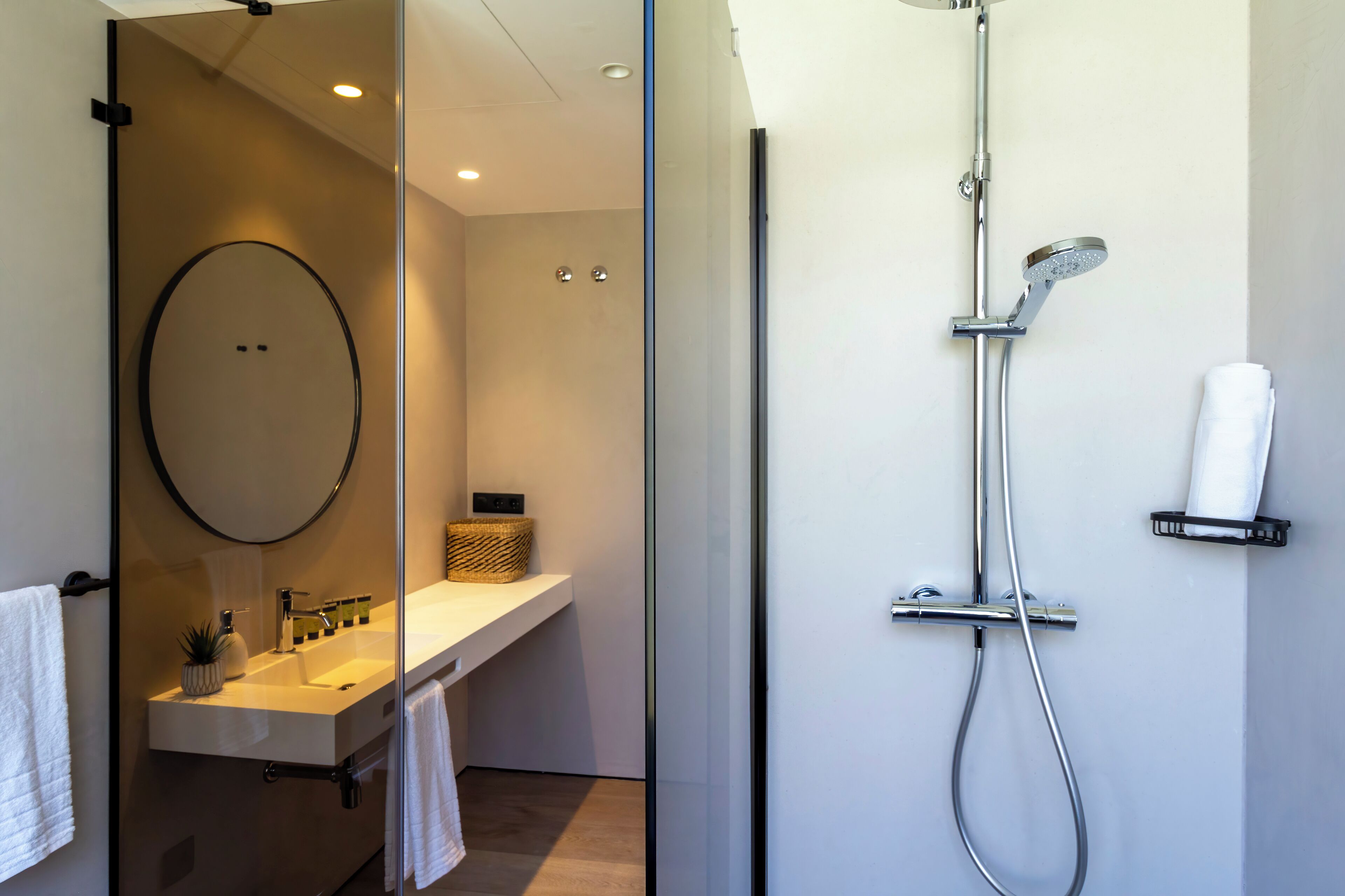 Ein modernes Badezimmer mit Duschkabine aus Glas, Waschbecken mit Spiegel und Handtuchhalter.