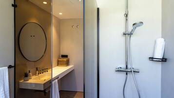 Ein modernes Badezimmer mit Duschkabine aus Glas, Waschbecken mit Spiegel und Handtuchhalter.