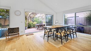Une pièce spacieuse avec une grande table à manger en bois, plusieurs chaises, un banc et une horloge au mur.