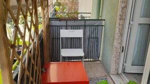 A small outdoor seating area with a red table and white chairs, enclosed by a bamboo fence. - Comeacasa. (Salerno)