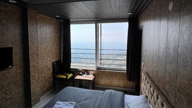 Habitación de hotel moderna con una cama grande, un escritorio pequeño y vista al océano.