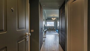 A hallway with a wooden floor, a desk, chairs, and a view of a cityscape through a window. - Carignano Luxury Suite by Wonderful Italy (Genoa)