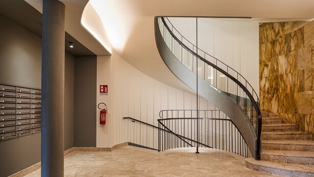 A modern interior with a curved staircase, marble flooring, and a fire extinguisher on the wall. - Carignano Luxury Suite by Wonderful Italy (Genoa)