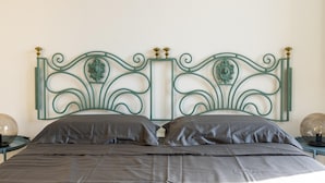 A bed with a metal headboard, two pillows, and a bedside table with a lamp. - Charming House in Cefal by Wonderful Italy (Cefalù)