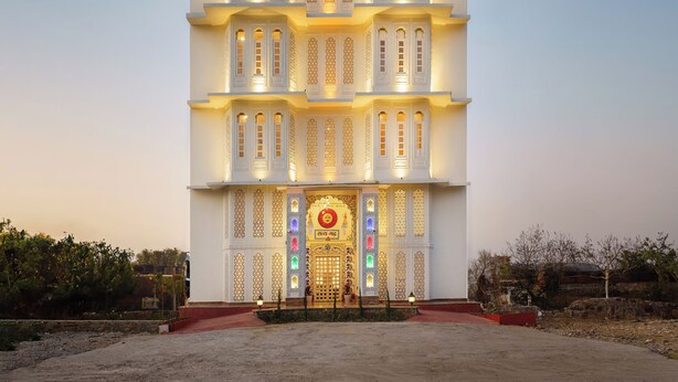 A multi-story building with a symmetrical facade, multiple balconies, and a central entrance with intricate designs. - Hotel Rudrakripa (Udaipur)