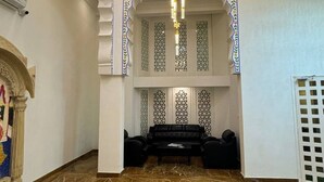 A spacious lobby with a marble floor, a black sofa set, and a decorative chandelier. - Hotel Rudrakripa (Udaipur)
