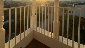A balcony with ornate white railings and columns, overlooking a cityscape with buildings and a mountain in the distance. - Hotel Rudrakripa (Udaipur)