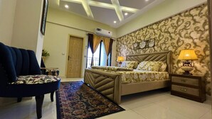 A hotel room with a bed, a chair, a nightstand, and a decorative lamp. - the Realtors inn Luxurious 1bed Apartment dha 2 (Islamabad)