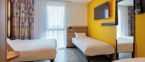 Una habitación de hotel con dos camas, televisión, espejo y escritorio.