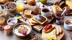 Una variedad de alimentos para el desayuno, como pasteles, frutas y bebidas, sobre una mesa de madera.