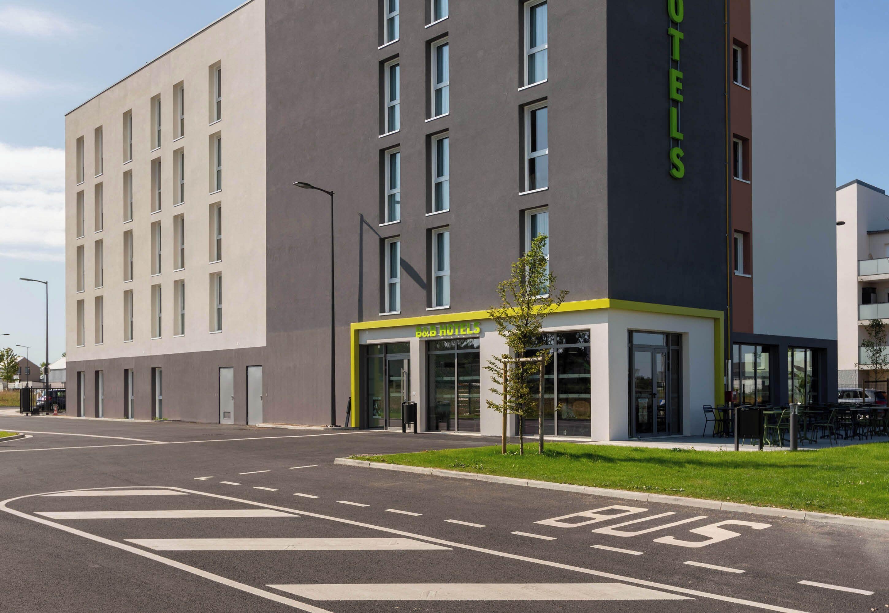 A modern hotel building with a flat facade, large windows, and a sign indicating it is a hotel.
