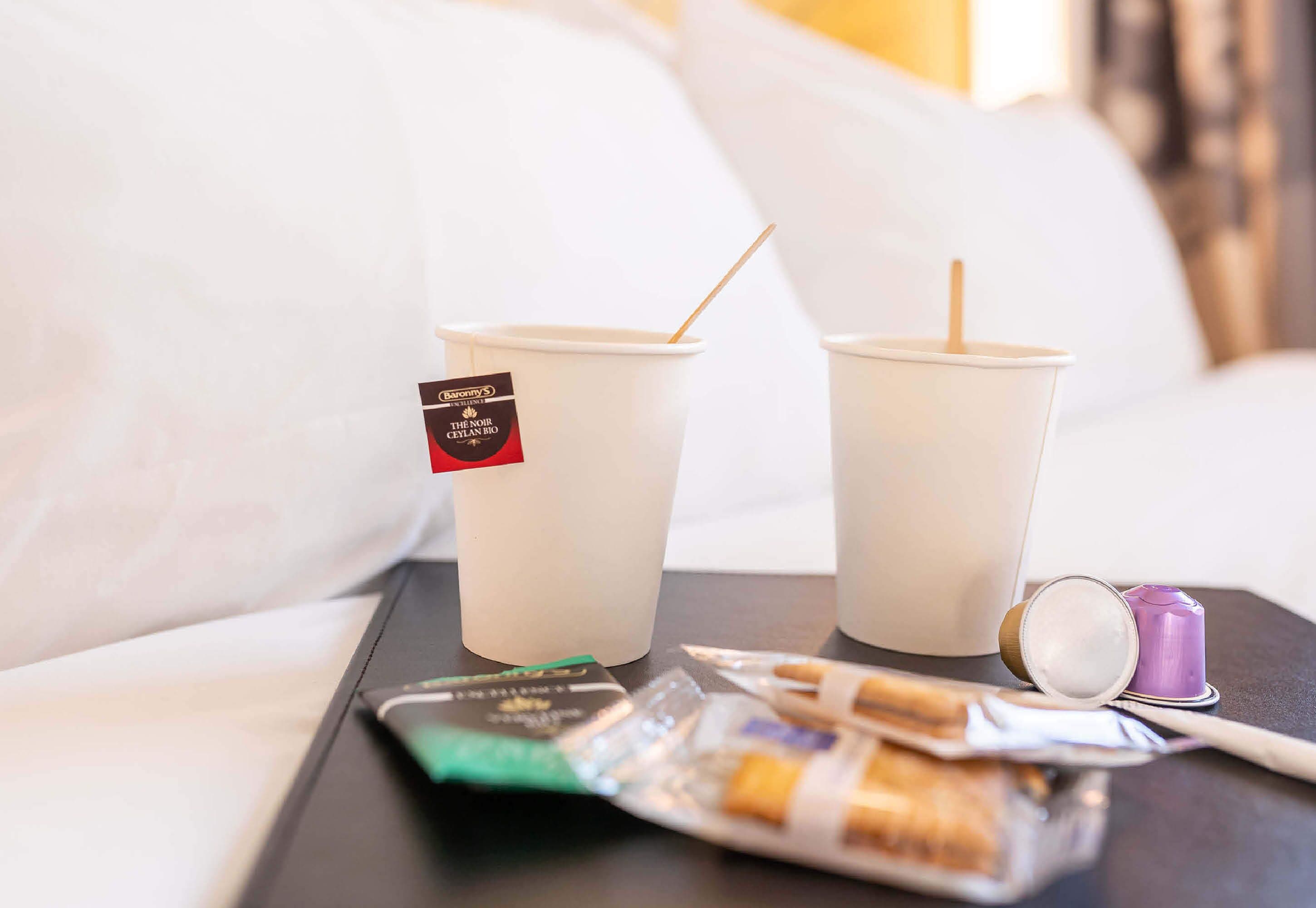 Dos vasos desechables con pajitas, un paquete de cigarrillos y un encendedor sobre una bandeja.