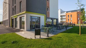 Un edificio moderno con un patio de restaurante y mesas al aire libre.