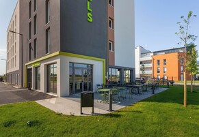 Un edificio moderno con un patio de restaurante y mesas al aire libre.