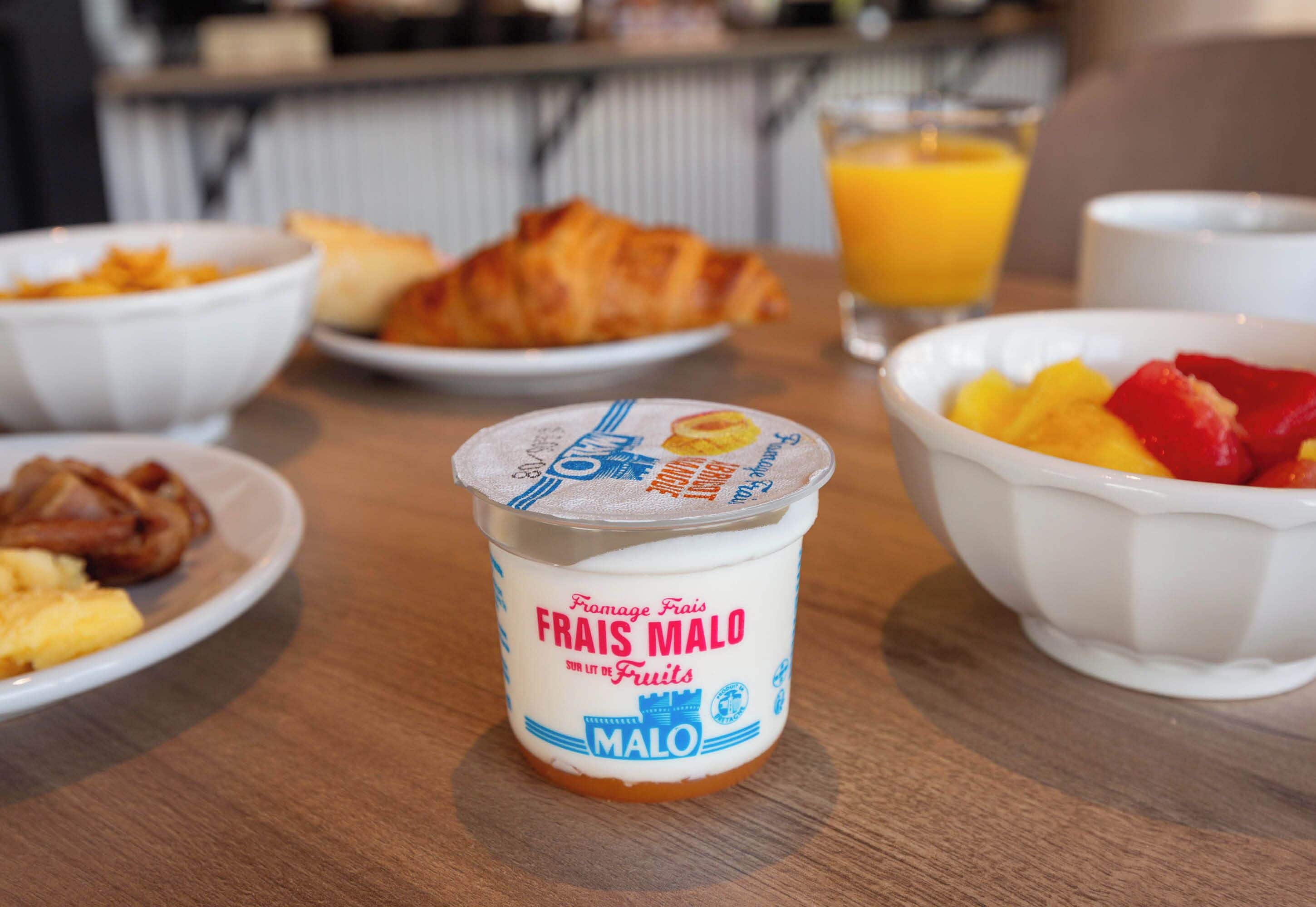 A breakfast table with a bowl of yogurt, a croissant, and a glass of orange juice.