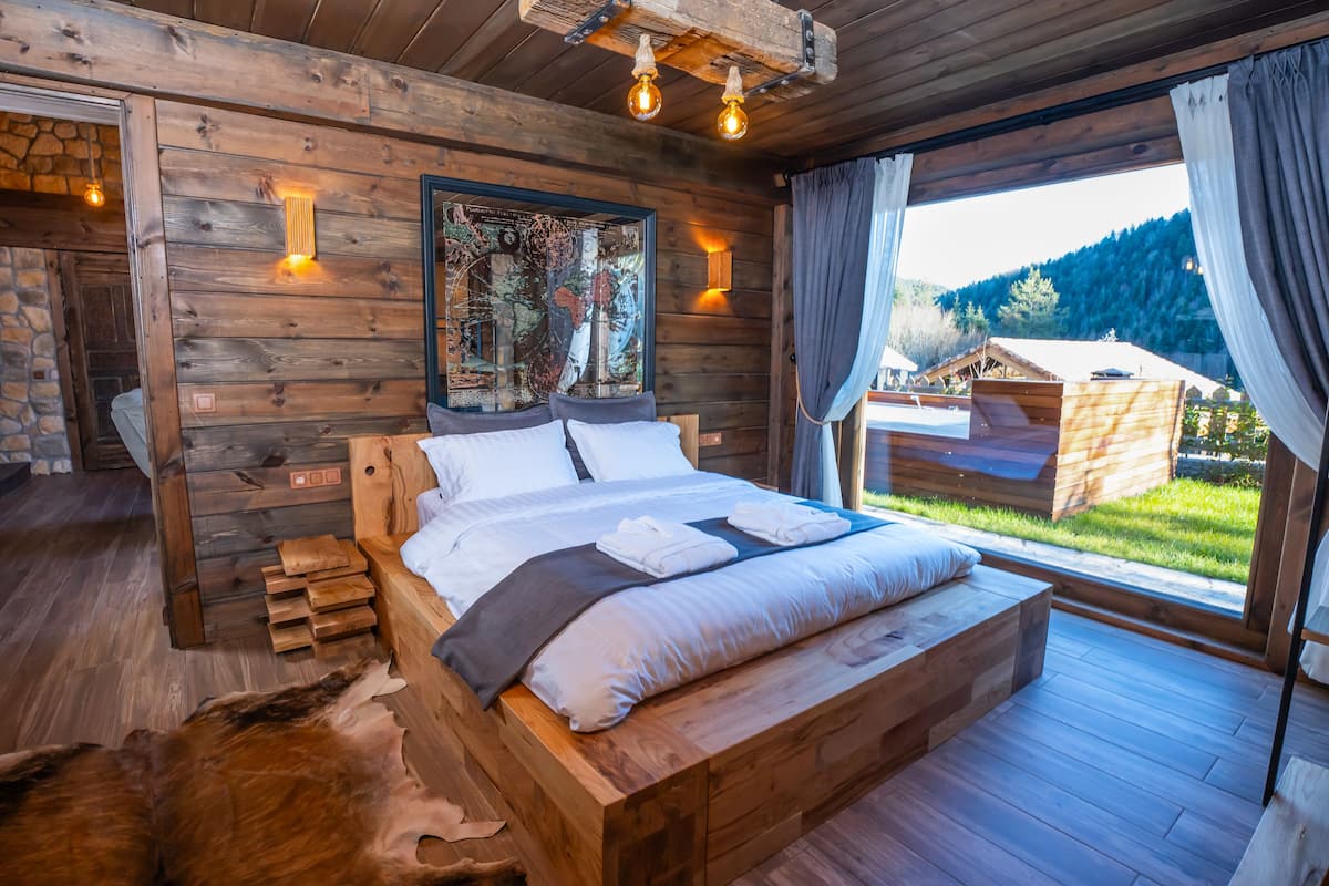 A wooden bedroom with a large bed, a map on the wall, and a view of the outdoors.