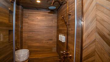 A wooden interior with a shower, a sink, and toiletries on the wall.
