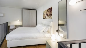 A modern bedroom with a large bed, bedside lamps, a desk, and a mirror. - Loft Garibaldi by Wonderful Italy (Genoa)