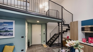 A modern living room with a blue sofa, a glass coffee table, and a staircase leading to an upper level. - Loft Garibaldi by Wonderful Italy (Genoa)