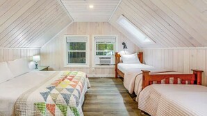 Une chambre mansardée chaleureuse, avec deux lits, des murs en bois et une lucarne.