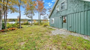 Un chalet rustique en bois, avec une allée en gravier et une vue sur un lac.