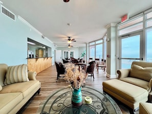 A spacious living area with a dining table, sofas, and a view of the ocean.