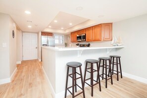 Una cocina moderna con armarios de madera, encimera blanca y una isla central con taburetes de bar.