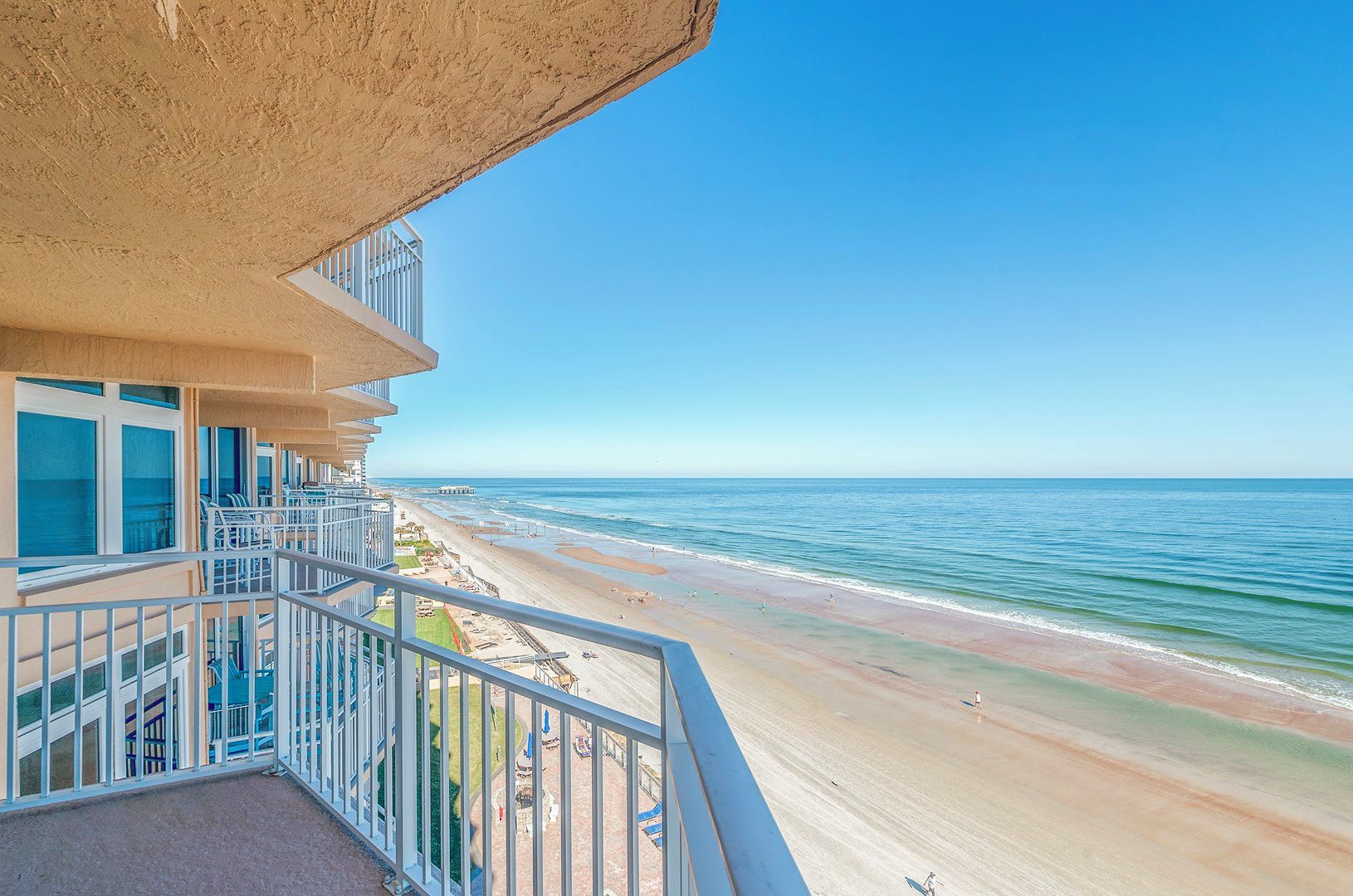 A beachfront hotel balcony with a view of the ocean and beach.