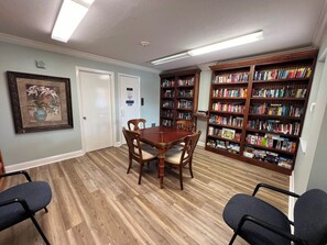 Een kamer met een houten tafel, stoelen en boekenplanken vol boeken.