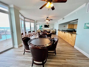 A spacious living area with a dining table, chairs, and a kitchen area with wooden cabinets.