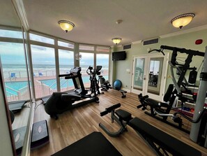 Une salle de sport équipée de machines de cardio, de matériel de musculation et offrant une vue sur l’océan.