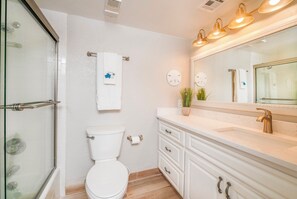 Une salle de bain avec une douche à parois de verre, des toilettes, un meuble-lavabo avec un miroir et un évier.