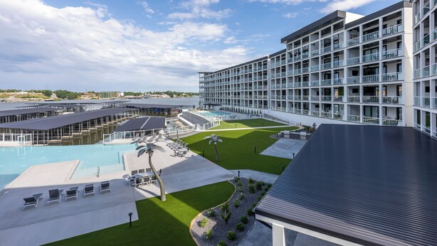 Un hôtel moderne doté d’une grande piscine, de nombreux balcons et d’une pelouse bien entretenue.