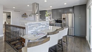 A modern kitchen with grey cabinets, stainless steel appliances, and a marble island. - Spacious Home & Lake Access, Lake Views Throughout (Lake Ozark)