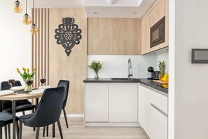 A modern kitchen with a built-in island, white cabinetry, and a decorative wall piece.