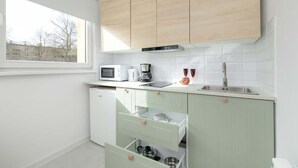 A modern kitchen with white cabinets, a microwave, a coffee maker, and a sink.