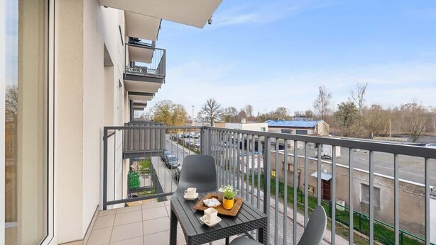 A balcony with a table, chairs, and a small plant.