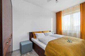 Une chambre d’hôtel avec un lit, une petite table de chevet, une armoire et une fenêtre avec des rideaux.