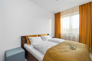 Une chambre d’hôtel avec un lit, une table de chevet, une fenêtre avec des rideaux et une vue sur la ville.
