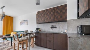 A modern kitchen with dark wooden cabinets, a built-in microwave, and a dining area with a table and chairs.