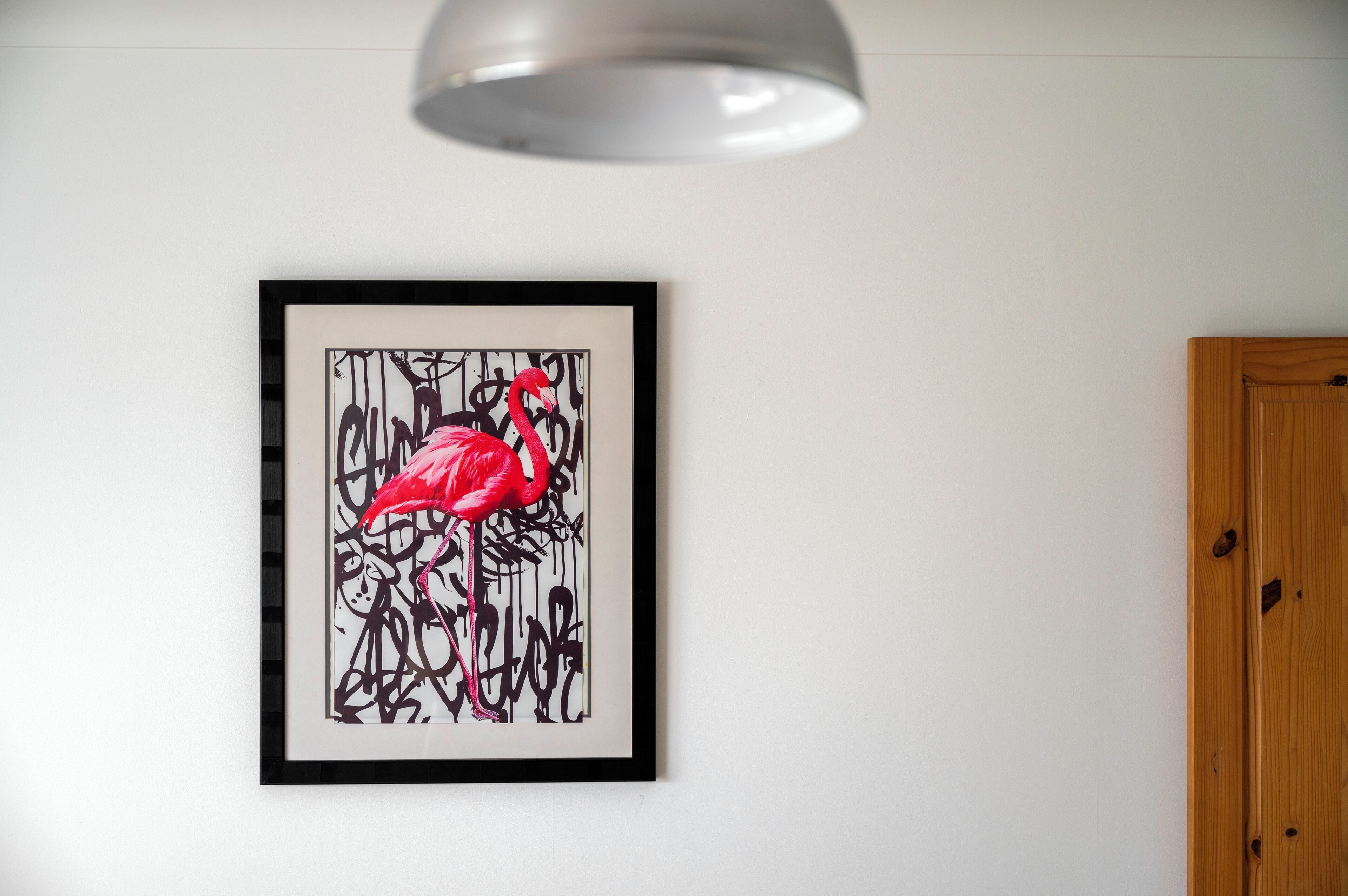 A framed artwork of a flamingo on a white wall.