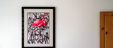 A framed artwork of a flamingo on a white wall.