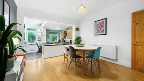 Una cocina moderna con armarios blancos, una mesa de comedor con sillas y una lámpara colgante.