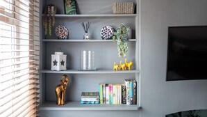 Una estantería con adornos, libros y un televisor.