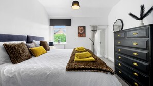 Un dormitorio con cama, cómoda, ventana y un cuadro en la pared.