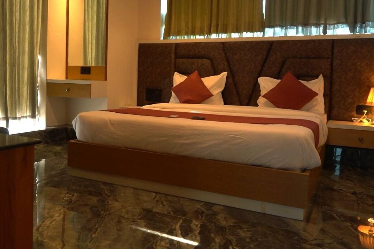 Una habitación de hotel con una cama grande, una mesita de noche y un espejo.