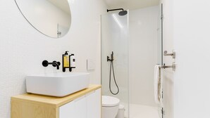 A modern bathroom with a white sink, a mirror, a toilet, and a glass-enclosed shower. - Feel Porto Corporate Housing Boavista I (Porto)