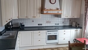 Eine Küche mit weißen Schränken, einer schwarzen Arbeitsplatte, einem Herd, einer Spüle und einer Uhr an der Wand.