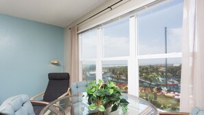 A balcony with a glass table, chairs, and a potted plant. - Gulfview II 611 Premier location, Great SpaceX View, Near beach (South Padre Island)