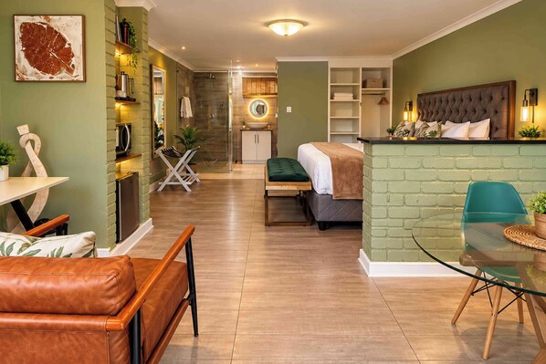 A modern living room with a sofa, a dining table, and a kitchen area with a refrigerator and microwave.